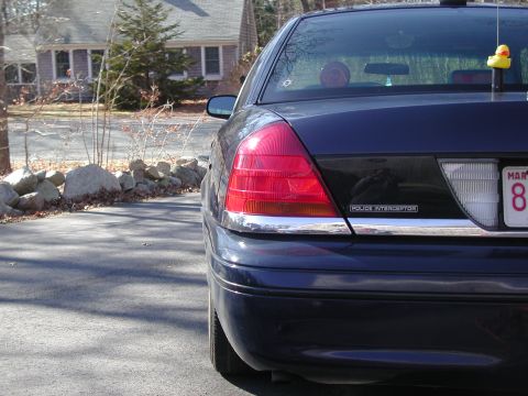 1999 Ford Crown Victoria - Rear view of a dark blue sedan with a "POLICE INTERCEPTOR" badge.
