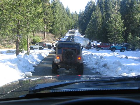 1989 Ford Bronco - A convoy of off-road vehicles navigates a snowy mountain pass.