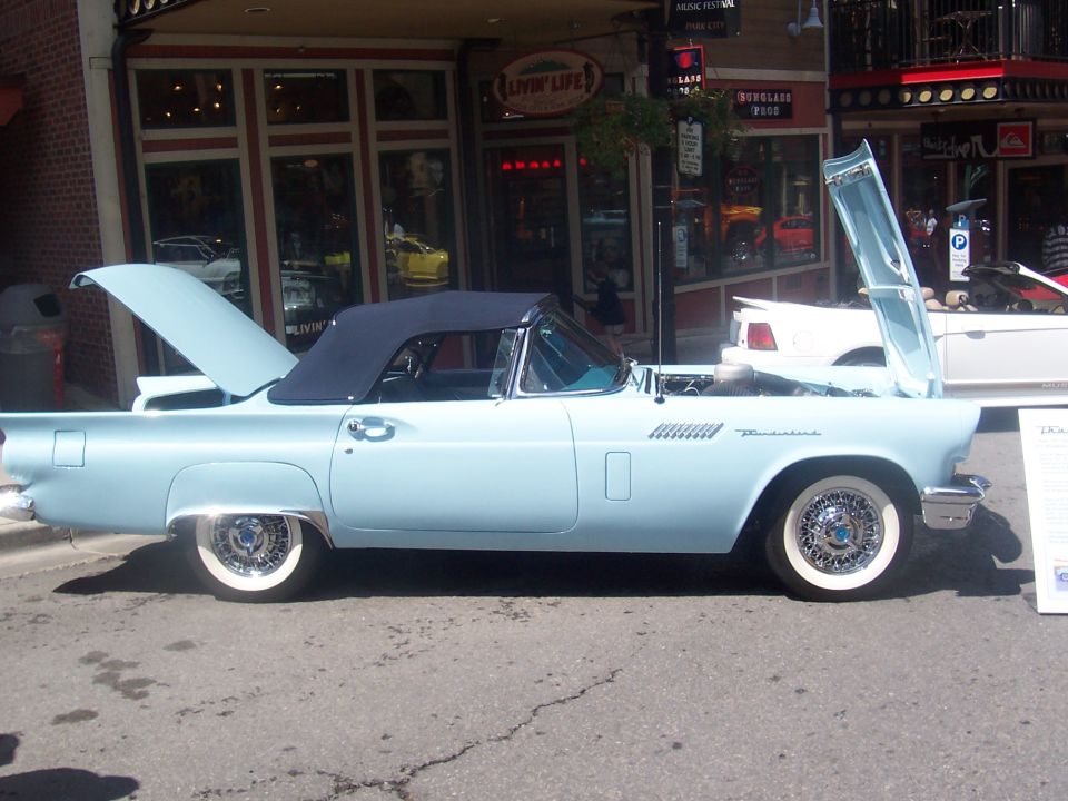 Light blue convertible with black top, hood and trunk open. Whitewall tires and wire wheels
