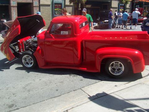 1973 Ford Mustang - A red pickup truck is displayed with its hood open at an outdoor event.