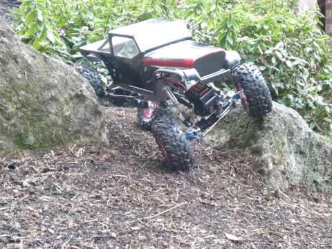 1993 Ford Bronco - This remote control rock crawler is navigating a challenging outdoor terrain with large rocks and loose dirt.