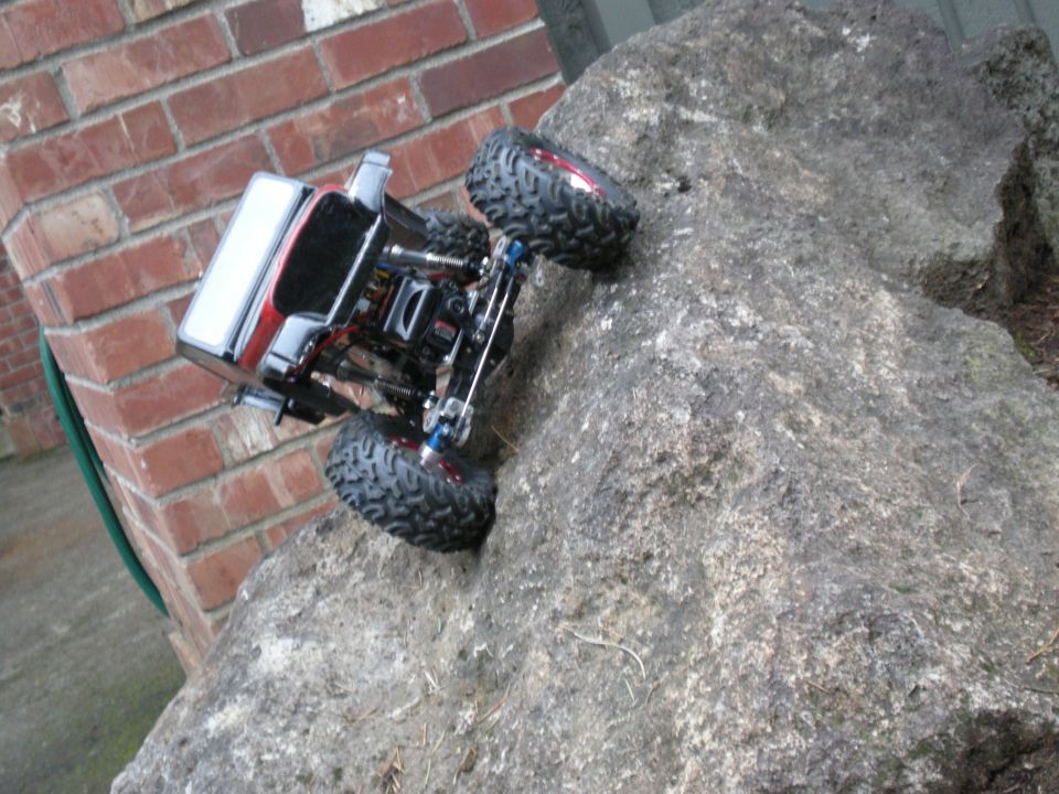 Red and silver RC rock crawler on a large rock