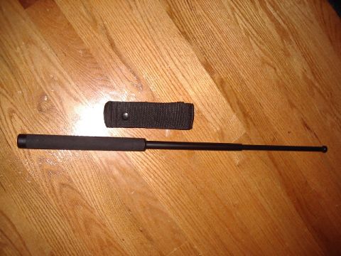 1985 Ford Bronco - Telescopic baton and its carrying sheath are displayed on a wooden surface.