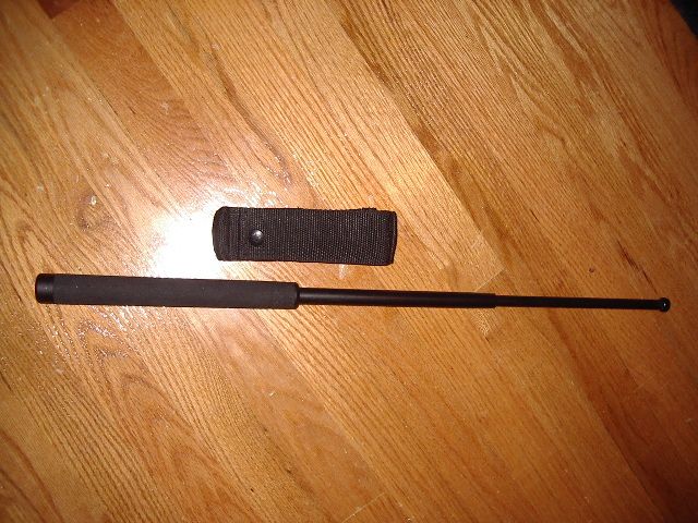 Telescopic baton and black fabric sheath on wooden floor
