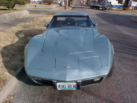 1977 Chevrolet Corvette - A light blue 1977 Chevrolet Corvette is parked on a street, showing its distinctive front end and hood scoop.