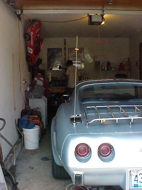 1977 Chevrolet Corvette - The rear of a light blue 1977 Chevrolet Corvette is visible, dual round taillights and a chrome luggage rack.