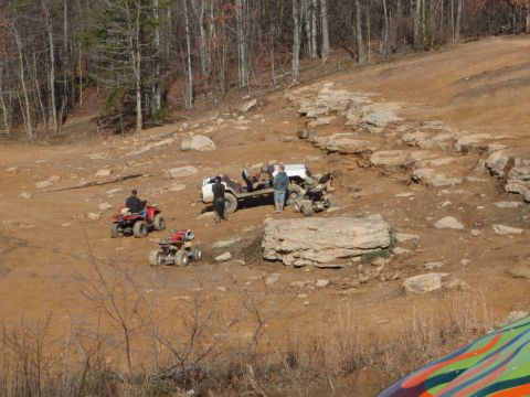 1991 Ford F-150 - People and off-road vehicles are gathered on a dirt trail in a wooded area.