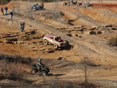 1991 Ford F-150 - Multiple off-road vehicles navigate a challenging dirt track with spectators observing the action.