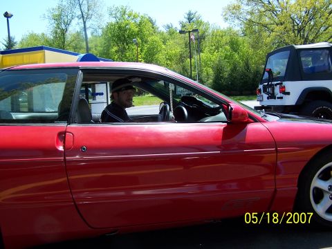 1996 Ford Probe - A man drives a red coupe, with a white Jeep visible in the background. The photo is dated May 18, 2007.