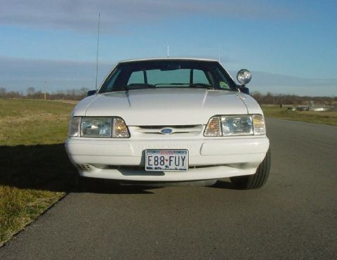 1993 Ford Mustang - White 1993 Ford Mustang parked on an asphalt road with a grassy field in the background.