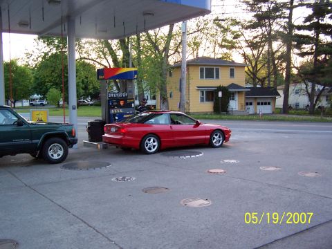 1996 Ford Probe - A red 1996 Ford Probe is at the gas station, with a green SUV also present.