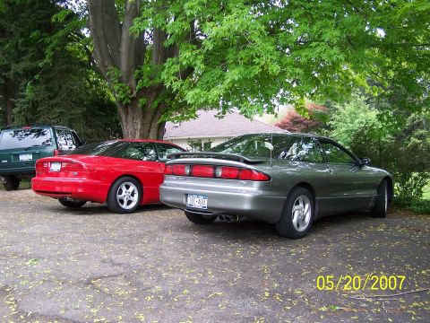 1996 Ford Probe - Two Ford Probes and a Jeep Cherokee are parked in a driveway on a sunny day.