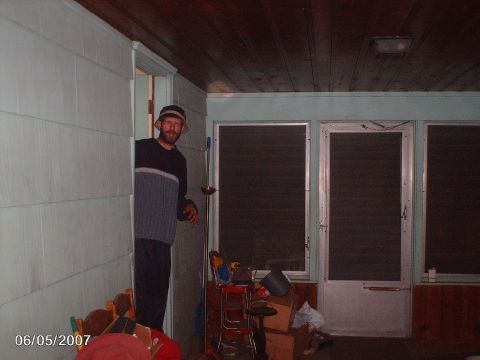 1996 Ford Probe - A man wearing a hat and a two-toned sweater peeks out from a doorway onto a porch with screened windows.