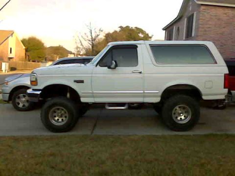 1993 Ford Bronco - A white Ford Bronco is parked on the side of the road next to another vehicle.