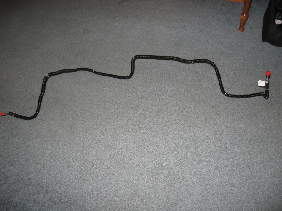 Black flexible fuel line with red caps on ends and a white label near one end
