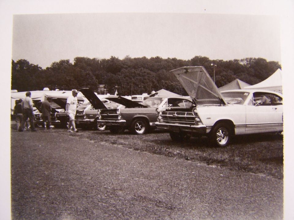 White Ford Ranchero with hood open, parked in a line of cars
