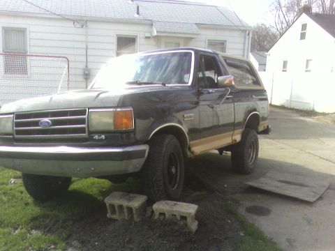 1990 Ford Bronco - This Ford Bronco is parked in a residential area with a house and fence visible.