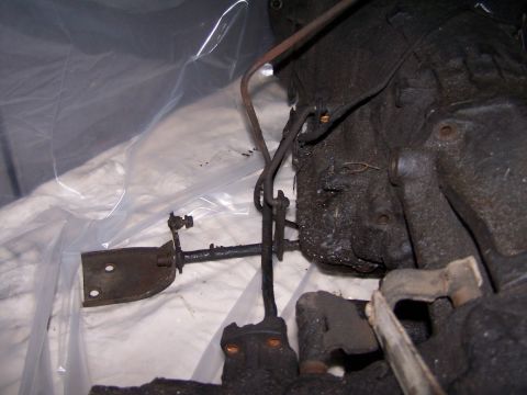 1990 Ford Bronco - Greasy vehicle transmission linkage mechanism with metal rods and brackets.