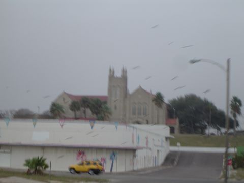 1989 Ford Bronco - A yellow SUV is parked in front of a building with a church visible behind it on an overcast day.