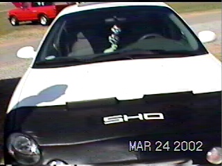 1997 Ford Taurus - Front view of a 1997 Ford Taurus SHO, with a red pickup truck visible behind it.