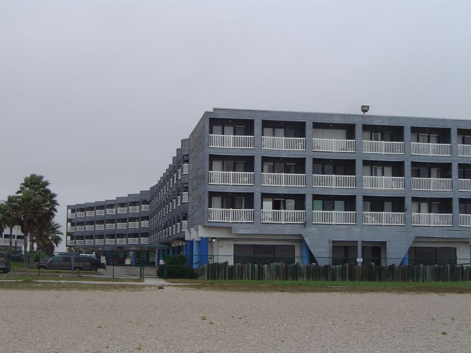 Gray building with white balconies and parked cars in front