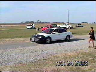 1997 Ford Taurus - A white sedan is parked on a gravel lot with other vehicles and a person standing nearby.