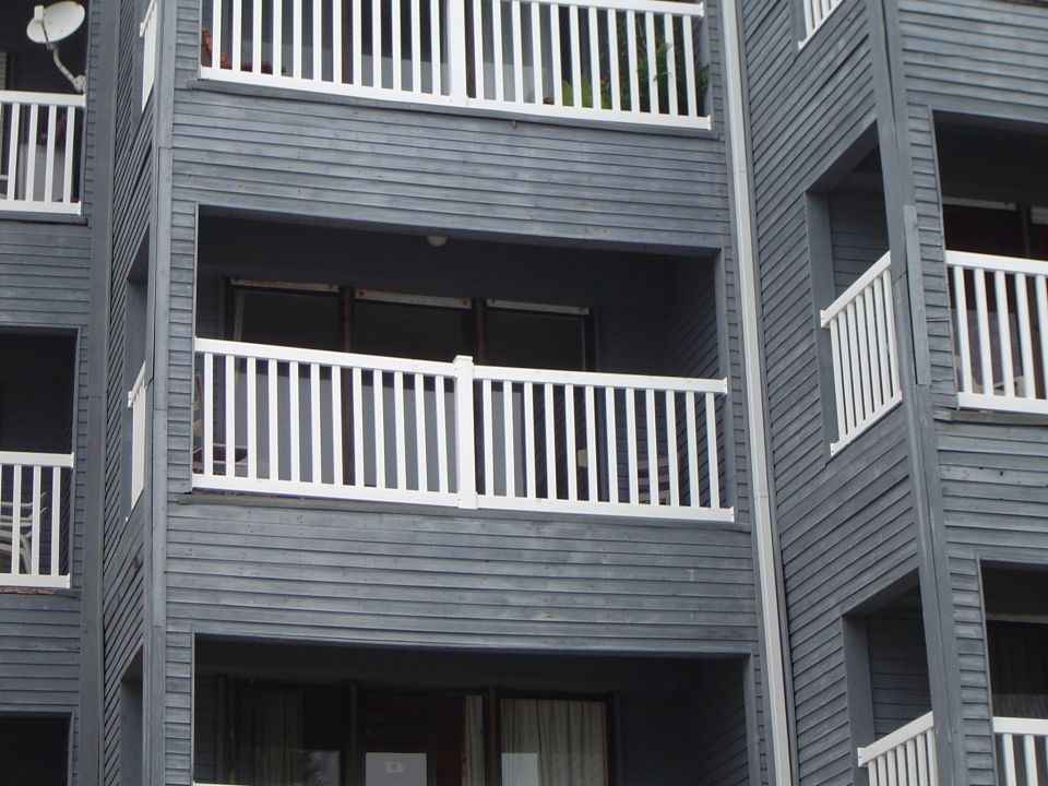 Exterior of a gray multi-story building with white-railed balconies
