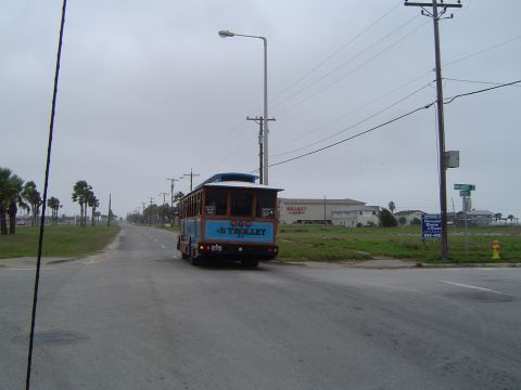 1989 Ford Bronco - A blue trolley bus with "B TROLLEY" written on the back drives down a street on an overcast day.