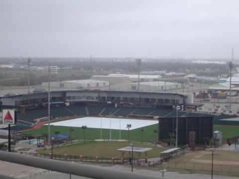 1989 Ford Bronco - A baseball stadium is viewed from above on a cloudy day, with the field covered by a large tarp.