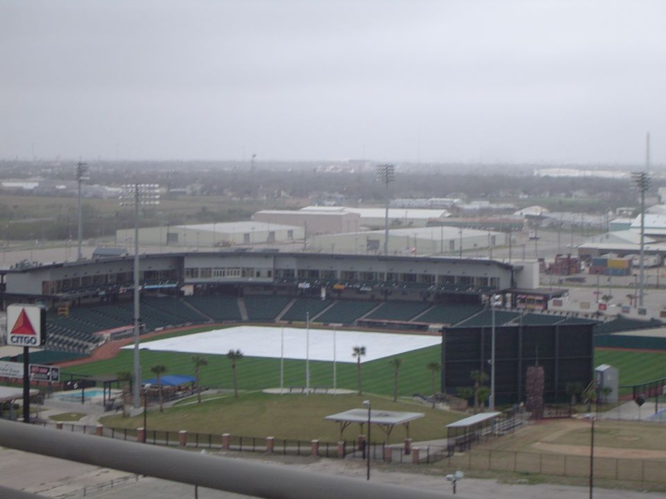 Baseball stadium with tarped field under overcast sky