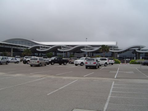 1989 Ford Bronco - Vehicles parked in a lot outside a large building with an architecturally distinctive roof.