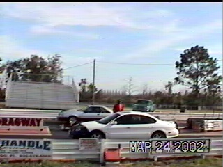 1997 Ford Taurus - Two cars are on a drag strip with a bleacher in the background and a date stamp of MAR 24 2002.