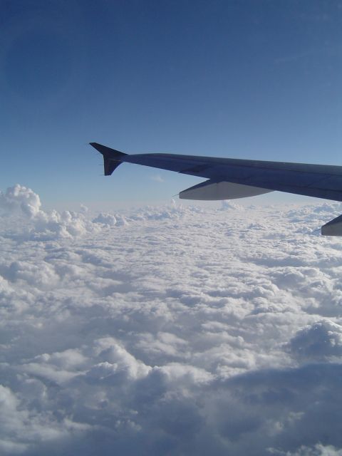 1989 Ford Bronco - View from an airplane window shows the wing and clouds below during a flight.