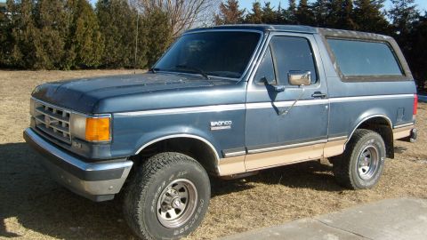 1995 Ford C-150 (Centurion Conversions) - 1987 Ford Bronco, 3-door SUV with removable top, parked on dry grass.