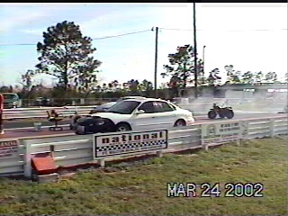 1997 Ford Taurus - A white sedan with a black hood is on a drag strip, with an ATV in the background. The image is dated March 24, 2002.