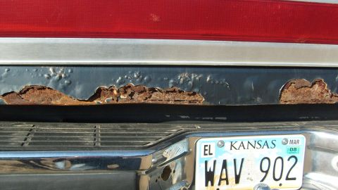 1995 Ford C-150 (Centurion Conversions) - Rust perforates the rear bumper of a vehicle, with a Kansas license plate visible below.