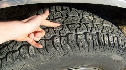 1995 Ford C-150 (Centurion Conversions) - A hand demonstrates tread depth on a tire, but no vehicle details are visible.