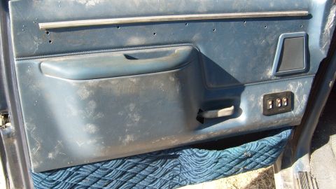1995 Ford C-150 (Centurion Conversions) - Close-up of a blue interior door panel, showing the armrest, speaker grille, and window control panel.