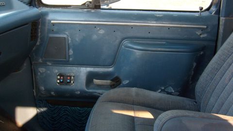 1995 Ford C-150 (Centurion Conversions) - The interior door panel shows wear and tear, with peeling material and a visible speaker and window controls.