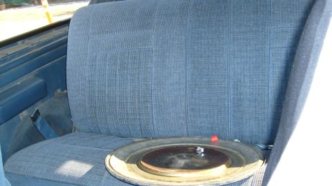 1995 Ford C-150 (Centurion Conversions) - Interior view of a blue fabric rear seat with a hubcap resting on the cushion.