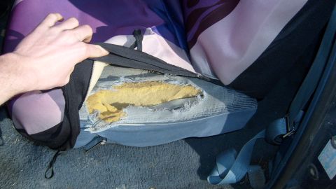 1995 Ford C-150 (Centurion Conversions) - Interior view of a damaged car seat with exposed foam and a hand adjusting the cover.
