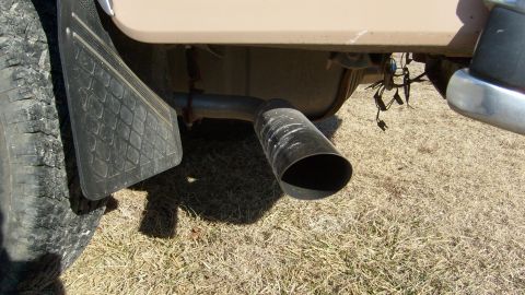 1995 Ford C-150 (Centurion Conversions) - Close-up of a vehicle's rear tire, mud flap, and exhaust pipe.