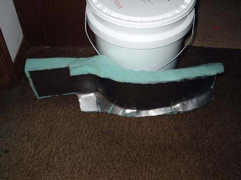 1978 Honda CB500T - A custom-made motorcycle fender part, covered in light blue foam padding, rests on a carpeted floor next to a white bucket.