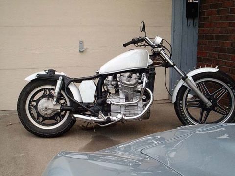 1978 Honda CB500T - A custom motorcycle with a white tank and exposed engine is parked in front of a garage door.
