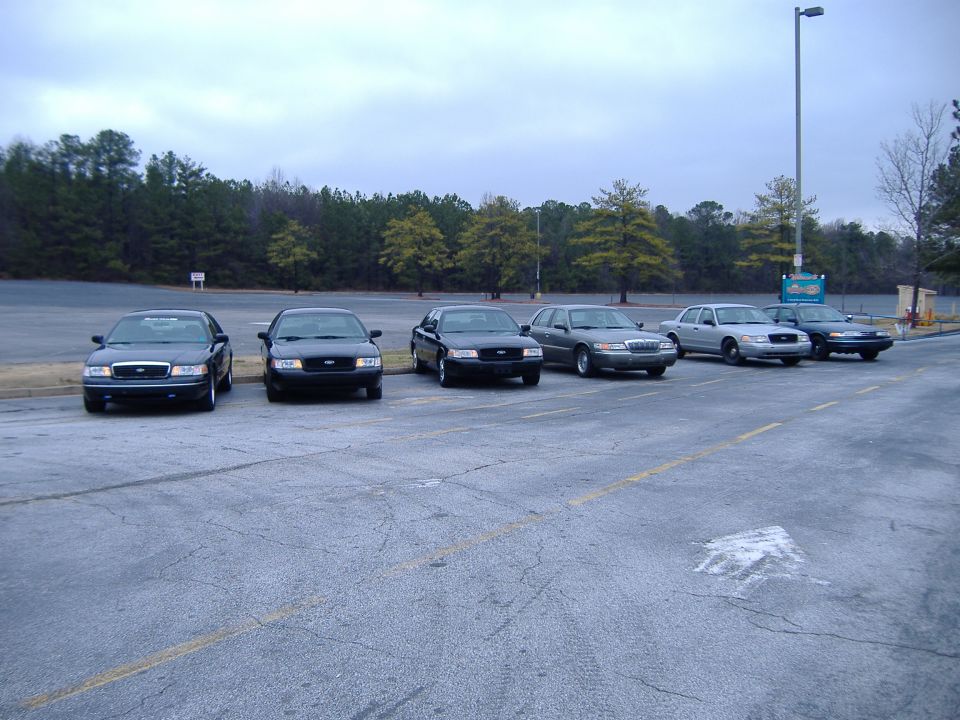 Six Ford Crown Victorias parked in a lot, front view
