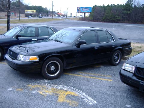 1996 Ford Crown Victoria - A black 1996 Ford Crown Victoria sedan is parked in a lot next to another similar vehicle.