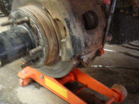 1996 Ford Bronco - Vehicle brake rotor and hub assembly being worked on, supported by an orange jack.