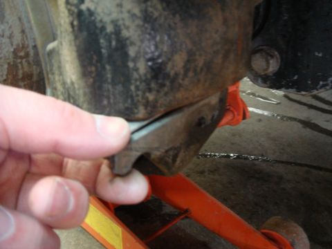 1996 Ford Bronco - A hand points to a damaged rubber bushing on a vehicle's suspension system, with an orange jack supporting the vehicle.