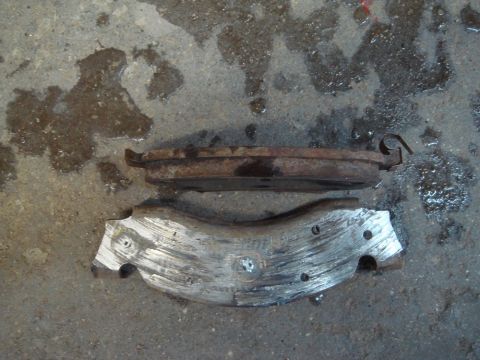 1996 Ford Bronco - Worn brake pads sit on a wet concrete surface, indicating a need for replacement.