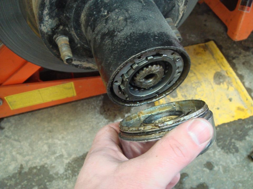 Close-up of a disassembled hub assembly with a hand holding a cap
